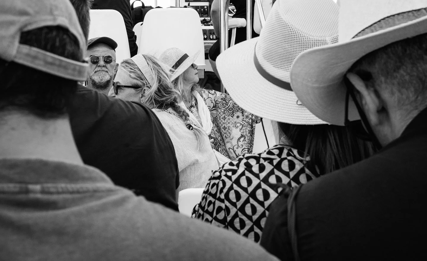 Passengers on a boat, faces and straw hats in black and white — street photograph by Giorgos Panagou